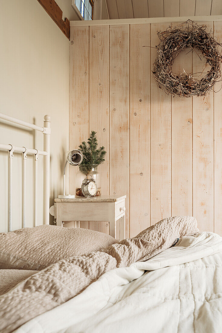 Schlafzimmer mit Holzverkleidung und beigefarbenem Bettbezug