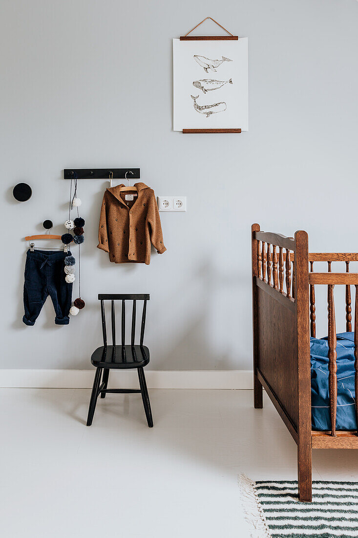 Kinderzimmer mit einer hölzernen Vintage-Babybett, schwarzem Stuhl und Wanddekorationen