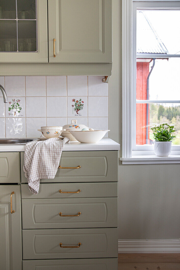 Country kitchen with grey-green cupboards and a view of the yard