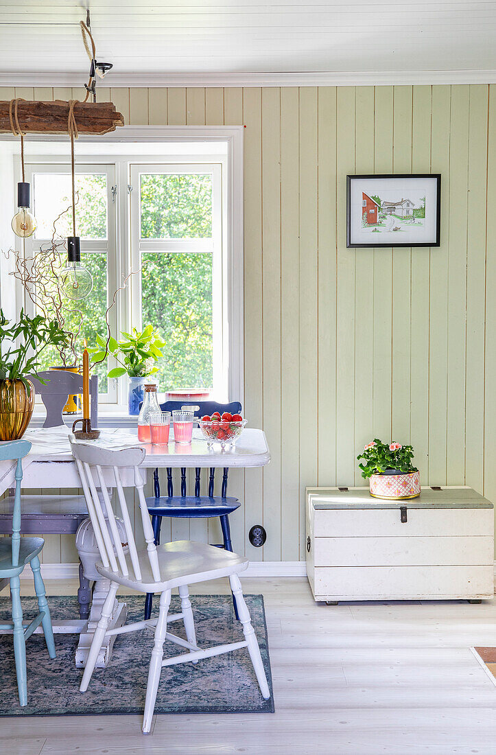 Dining area with wooden chairs and table by the window, pastel green wall paneling