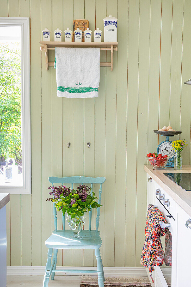 Country kitchen with turquoise wooden chair and bouquet of lilacs