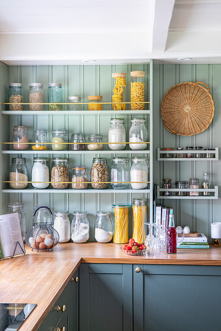 Open storage shelves with glass containers in a green country kitchen