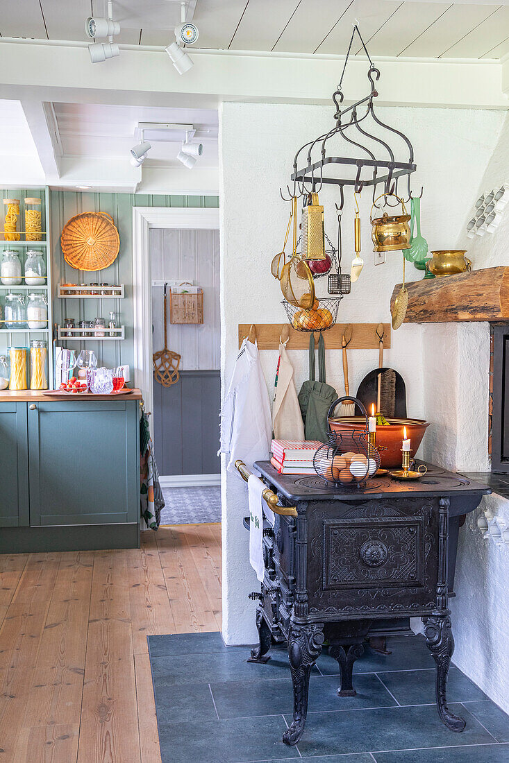 Vintage cooker, hanging kitchen utensils and candles in a cosy country kitchen