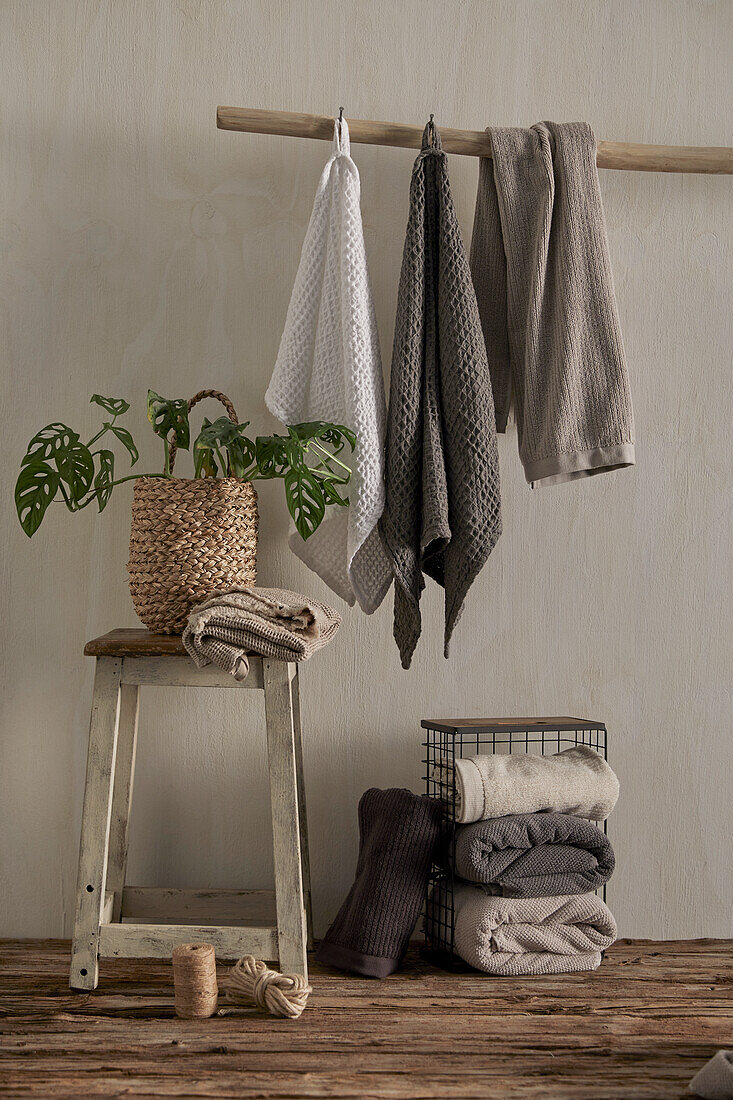 Stacked and hanging towels, rustic stool with plant