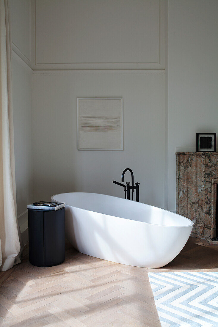 Freistehende Badewanne mit schwarzem Wasserhahn, Fischgrätparkett