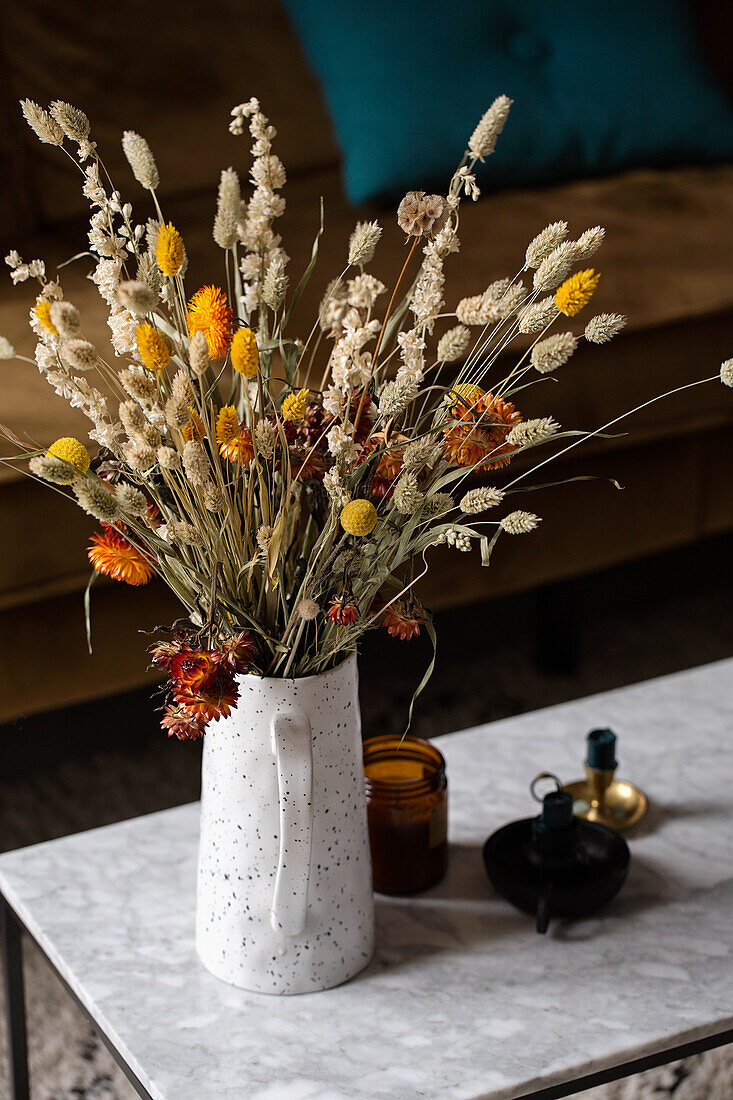 Bouquet of dried flowers in speckled vase on marble table