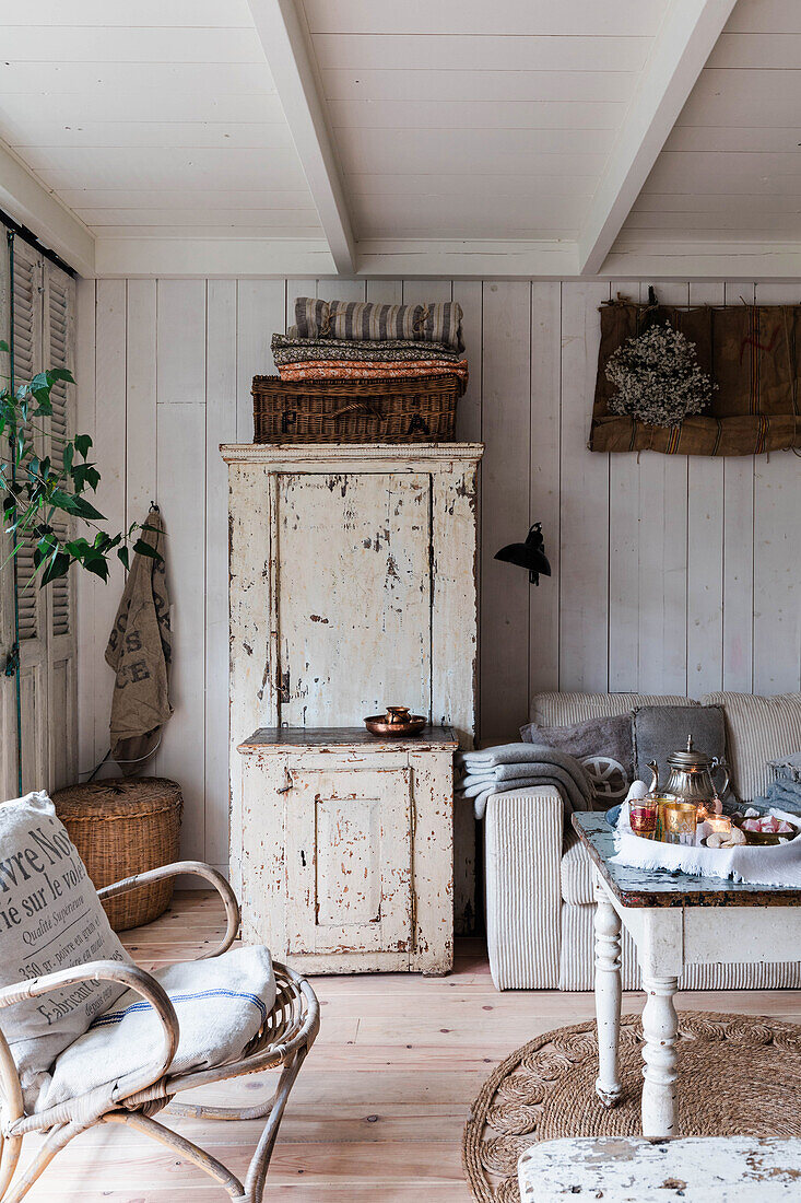 Living room with antique cupboard and linen cushions, shabby chic look