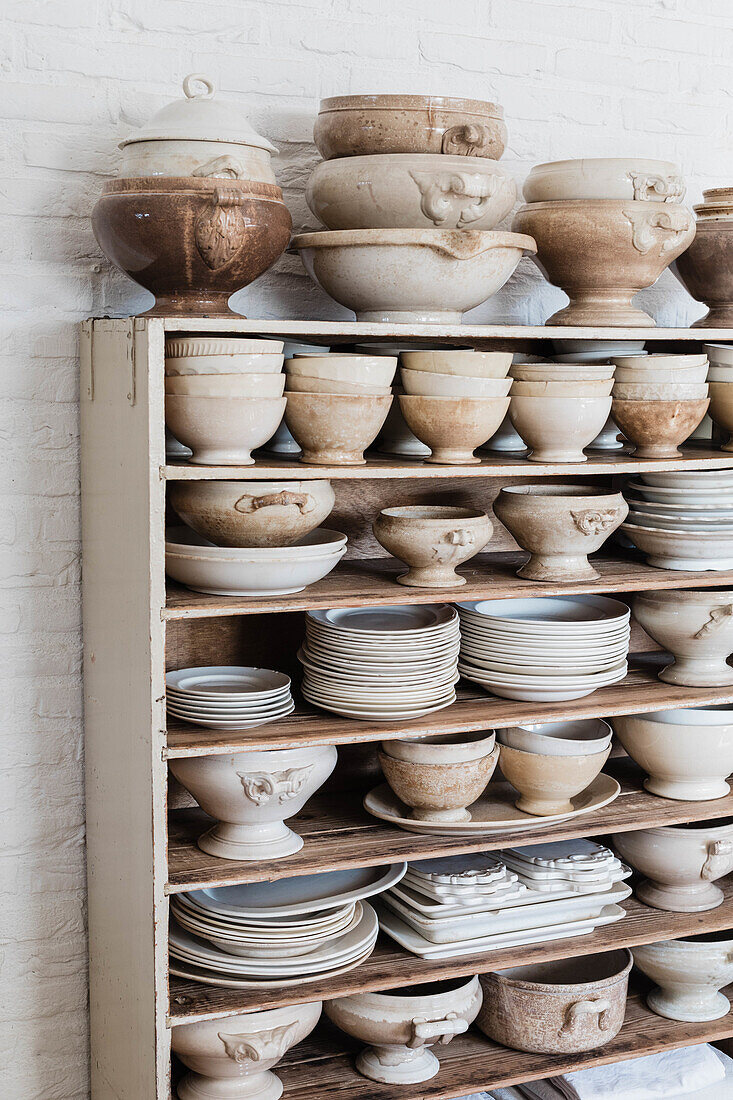 Shelves with rustic ceramic crockery against a white brick wall