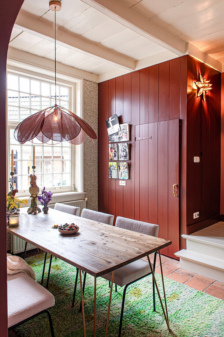 Dining area with wooden table, striking lamp and floor tiles with green carpet