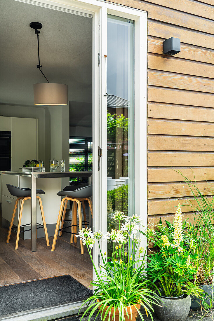 Modern kitchen with bar stools, view through open patio door