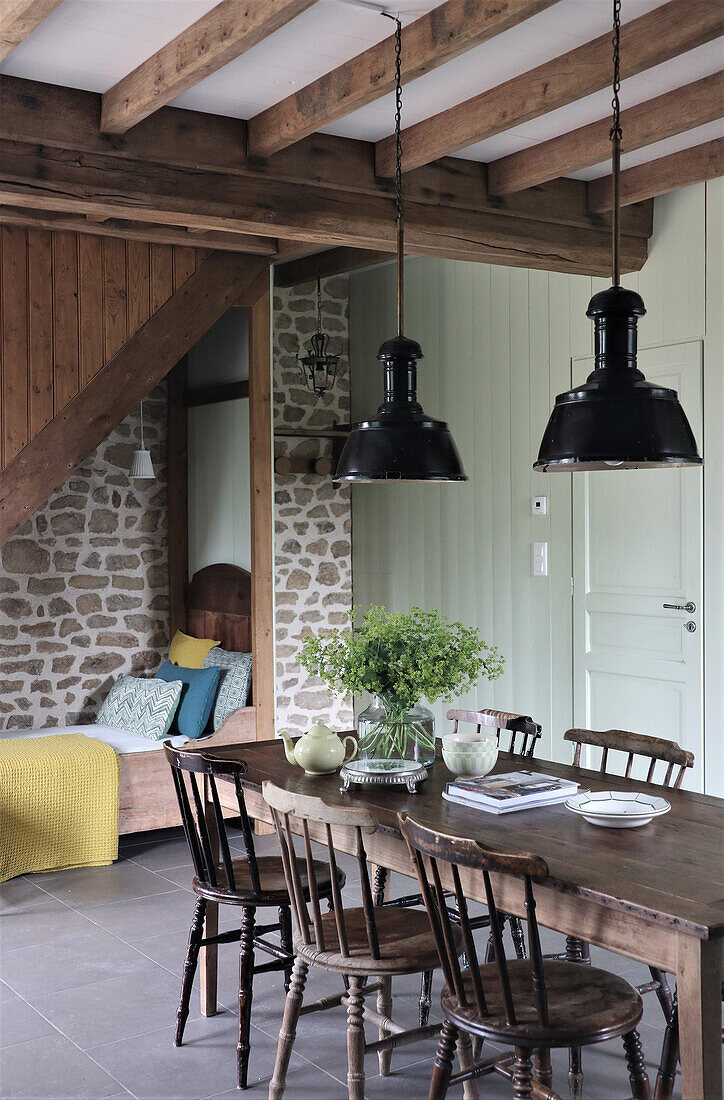 Dining area with wooden table, black pendant lights and natural stone wall