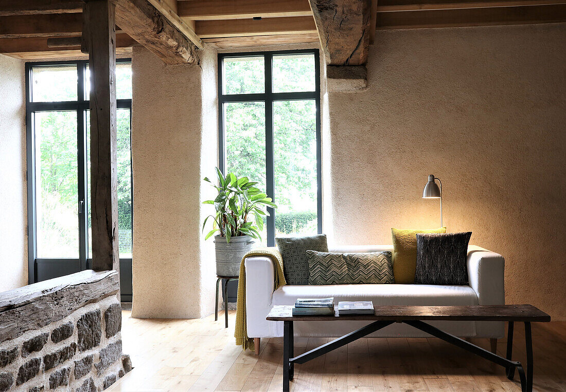 Living room with rustic wooden beams and natural stone wall, modern sofa and floor lamp