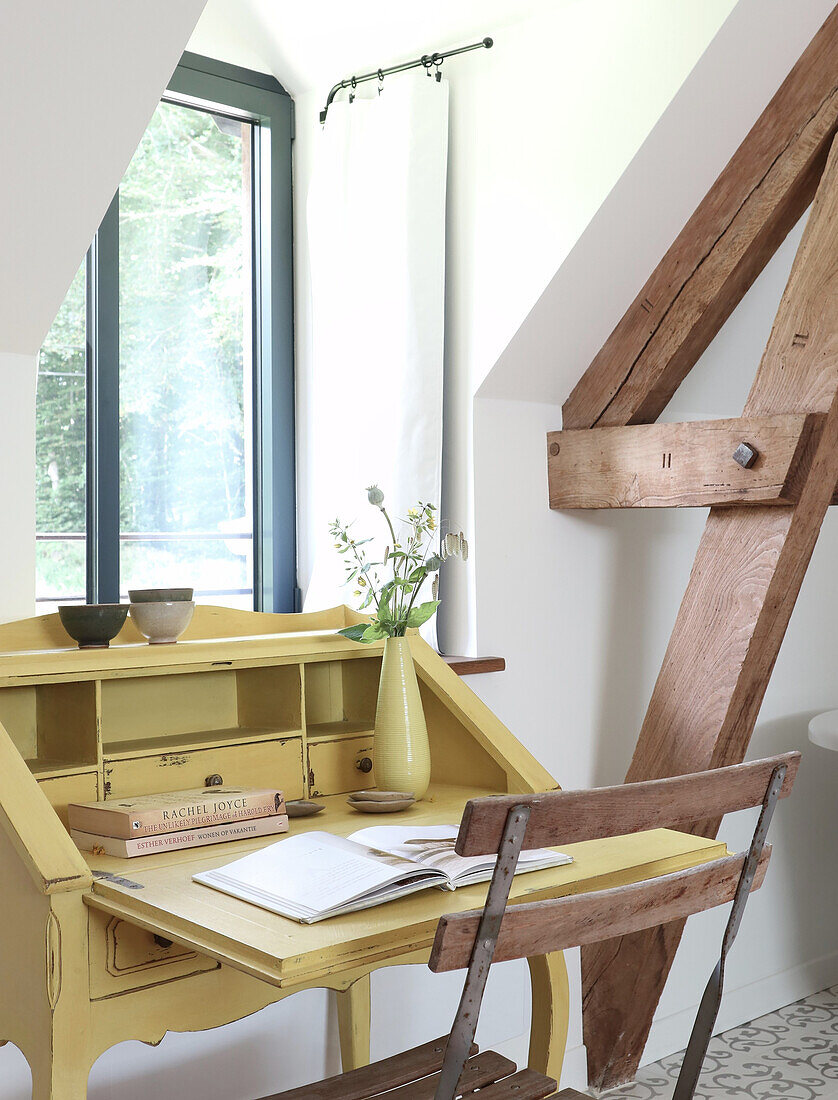 Gelber Sekretär mit Holzstuhl und Vase im Dachzimmer