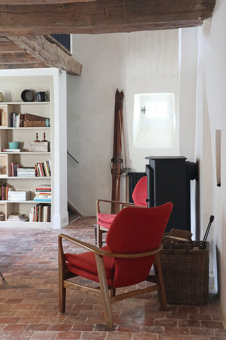 Living room with terracotta tiles, red armchairs and fireplace