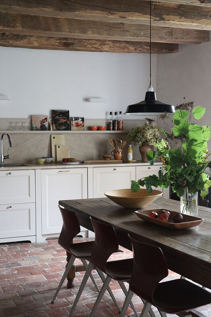 Wooden table with ceramic bowls in rustic kitchen with wooden beamed ceiling