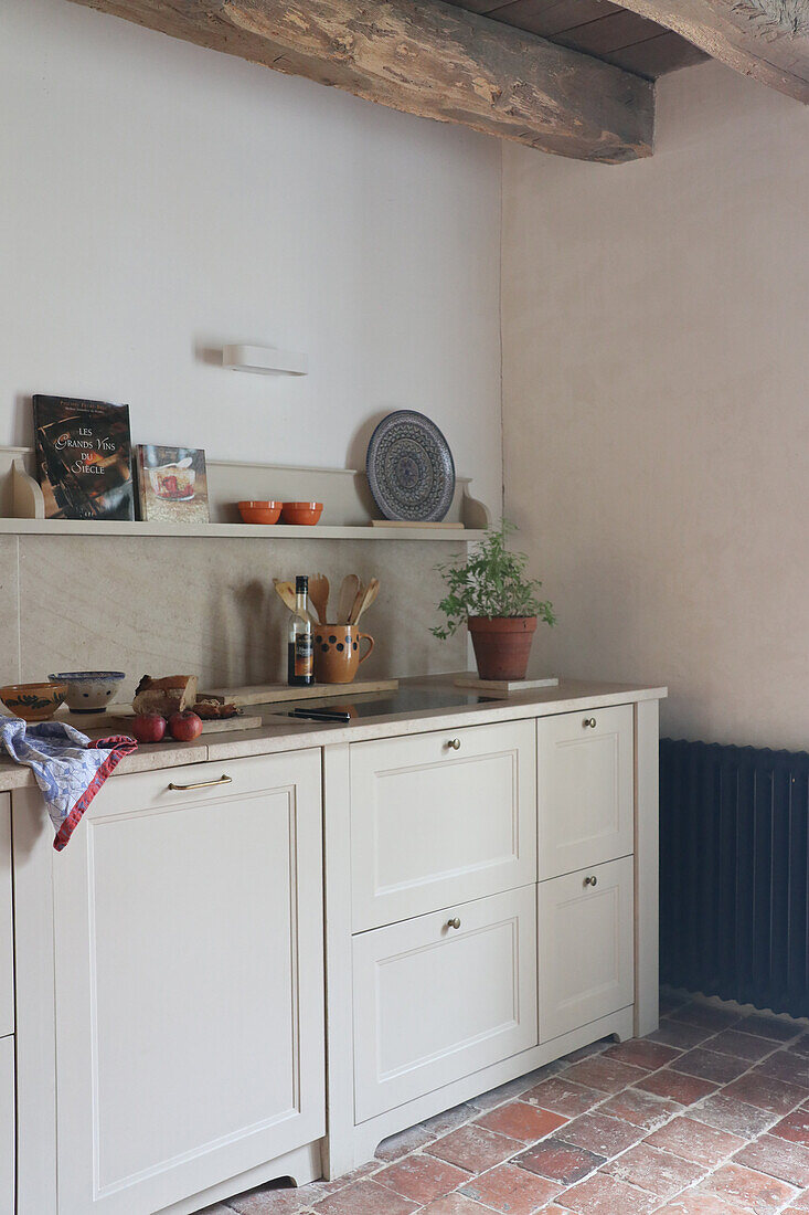 White country-style kitchen with terracotta floor and wooden beamed ceiling