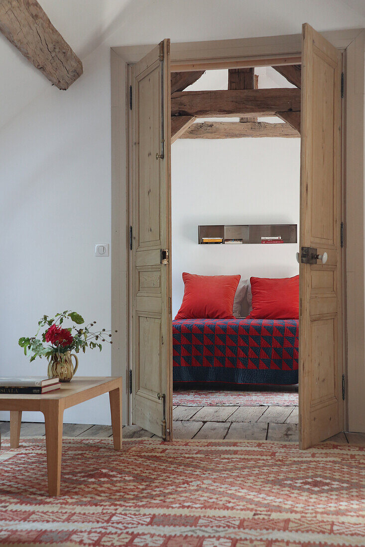 View of bedroom with antique wooden doors and bedspread with geometric pattern