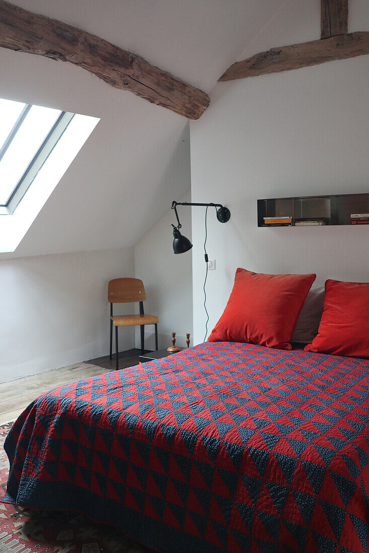 Bedroom with sloping ceiling and patchwork bedspread in blue and red