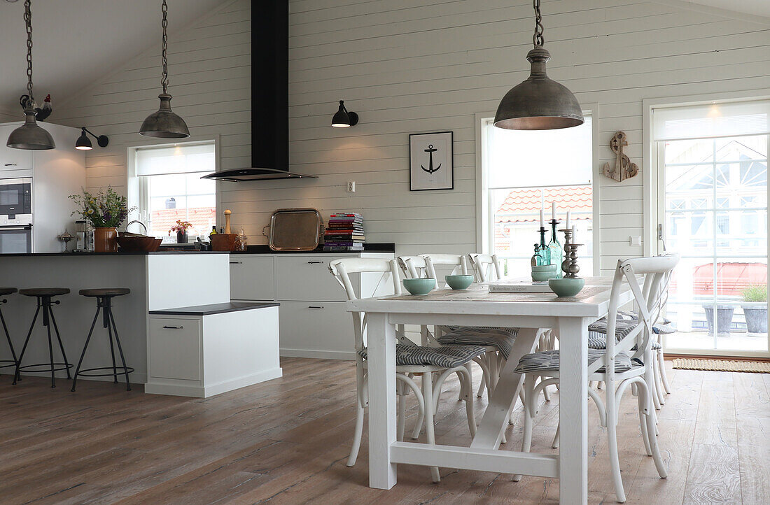 Open-plan Scandinavian-style kitchen and dining area with white wooden table and chairs