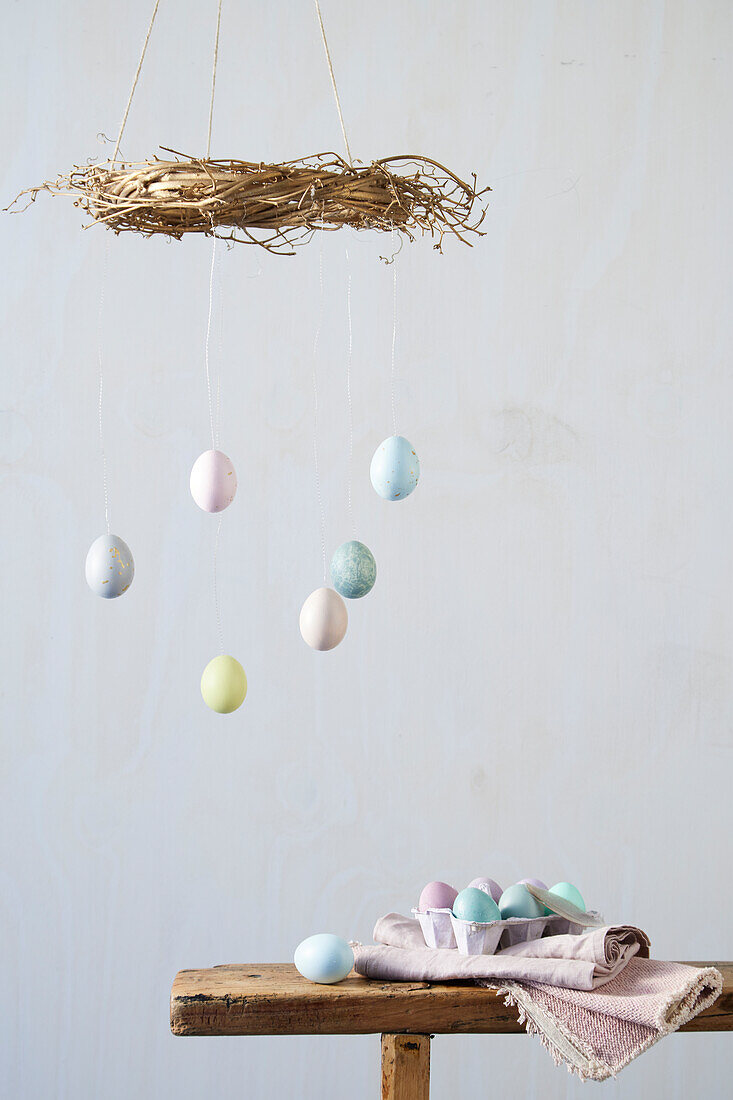 Creative Easter decoration mobile with pastel-colored eggs hangs over wooden table