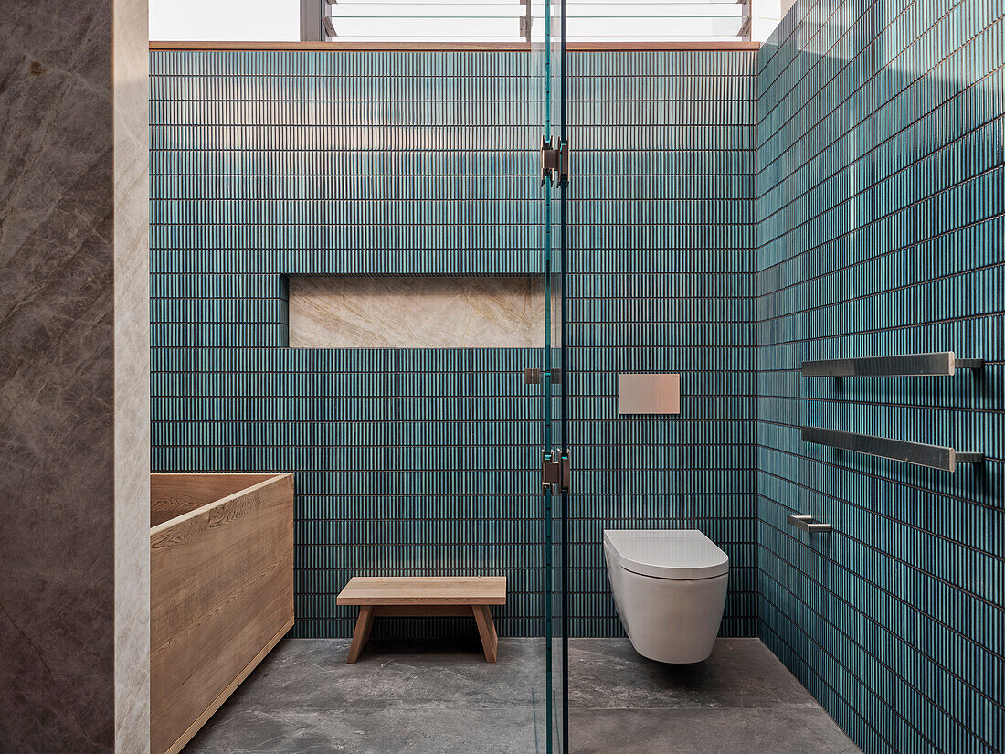 Bathroom en suite with blue tiles, wooden bathtub and glass doors