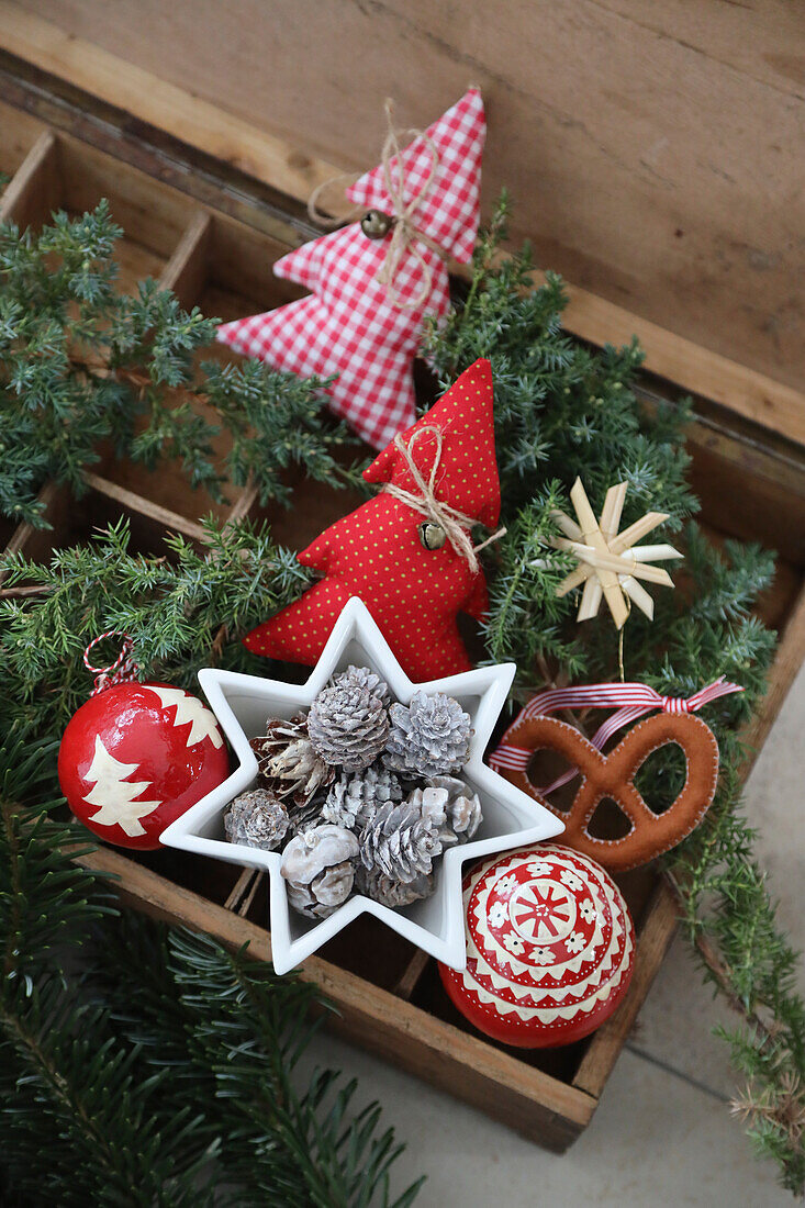 Holzkasten mit rotweißer Weihnachtsdeko, Sternschälchen, Zapfen, Kugeln