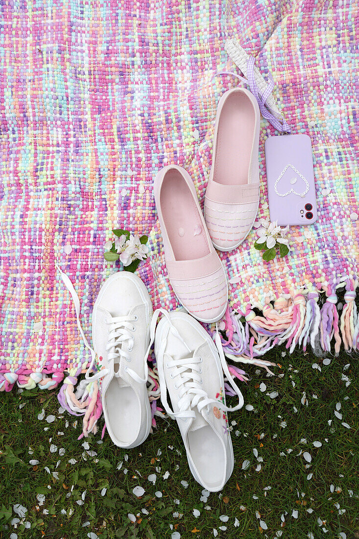 Sneakers and slippers on a colourful blanket in the garden