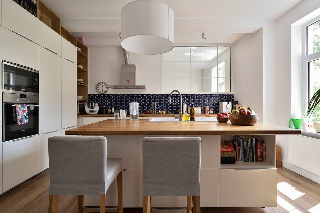 Modern kitchen with island, wooden worktop and dark blue tile backsplash