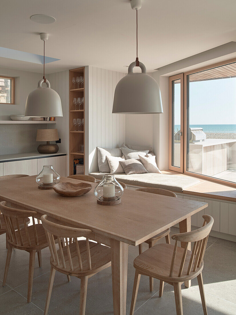 Dining area with wooden table and window seat overlooking the sea