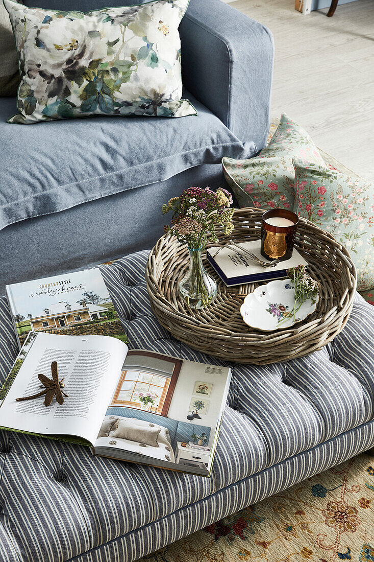 Striped upholstered ottoman with books and rattan tray in the living room