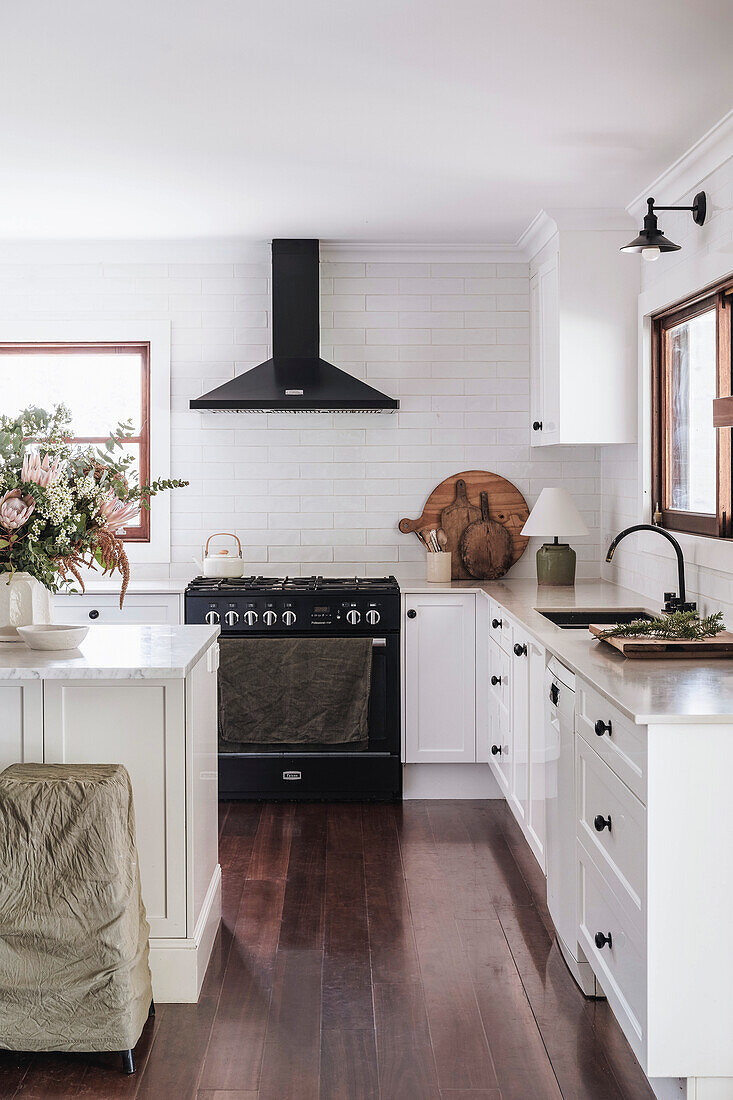 Bright kitchen with white tiled backsplash and dark wooden floor