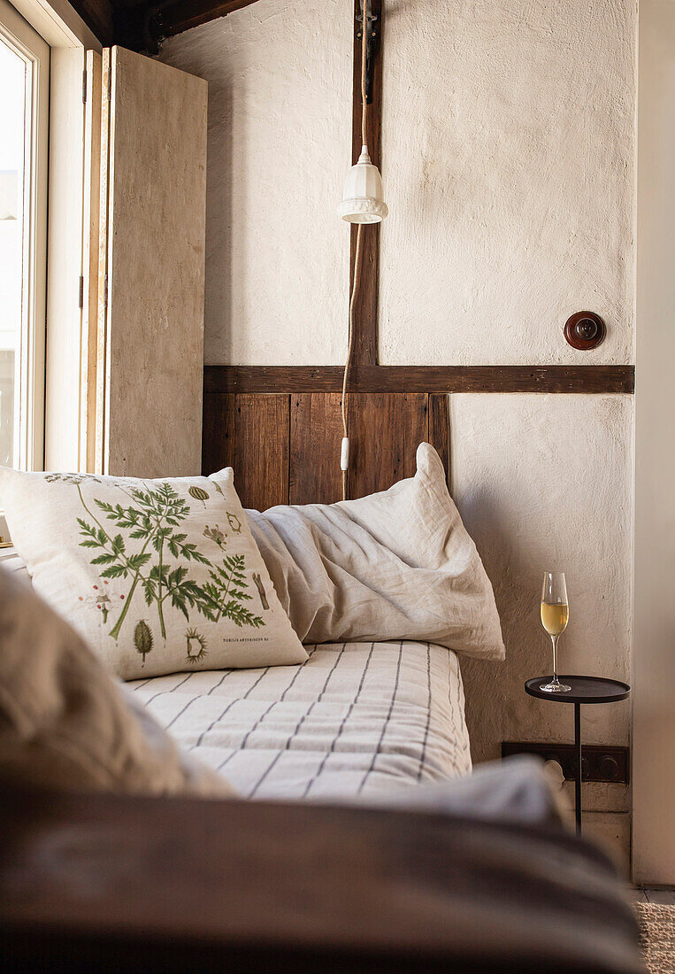 Cozy reading corner with linen cushions and side table with champagne glass