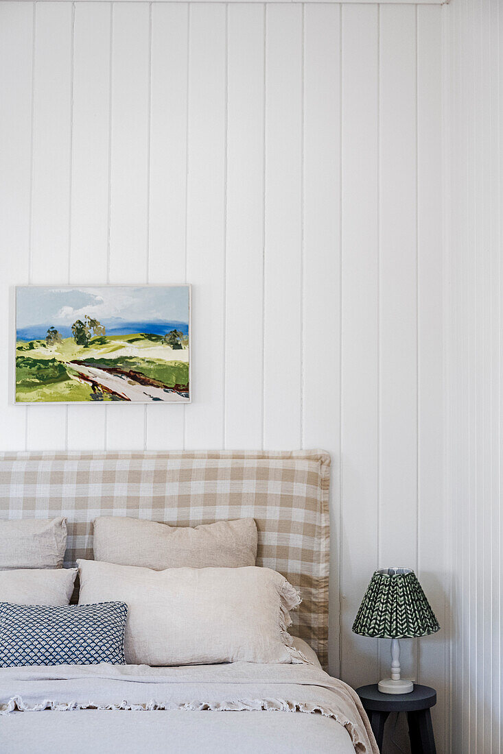 Bedroom with checkered headboard and landscape picture on the wall