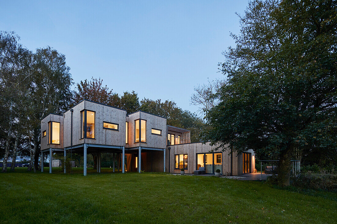 Modern wooden house on stilts at dusk, Scawby Brook, UK