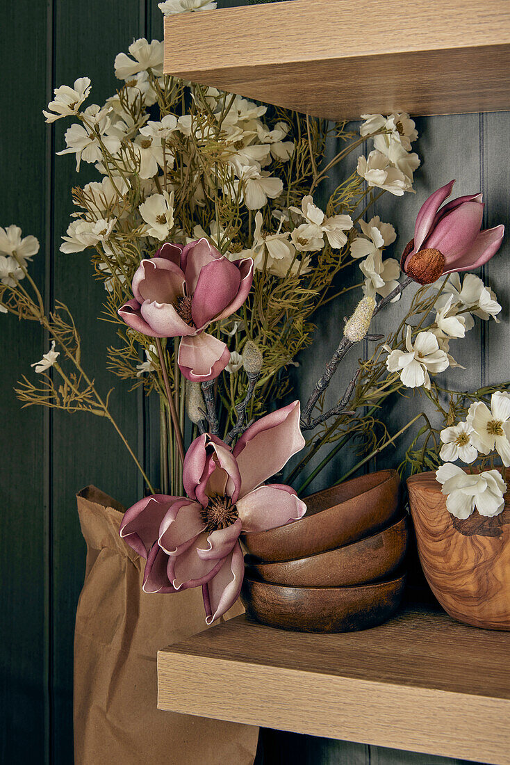 Decorative wooden bowls on shelf, flowers next to them