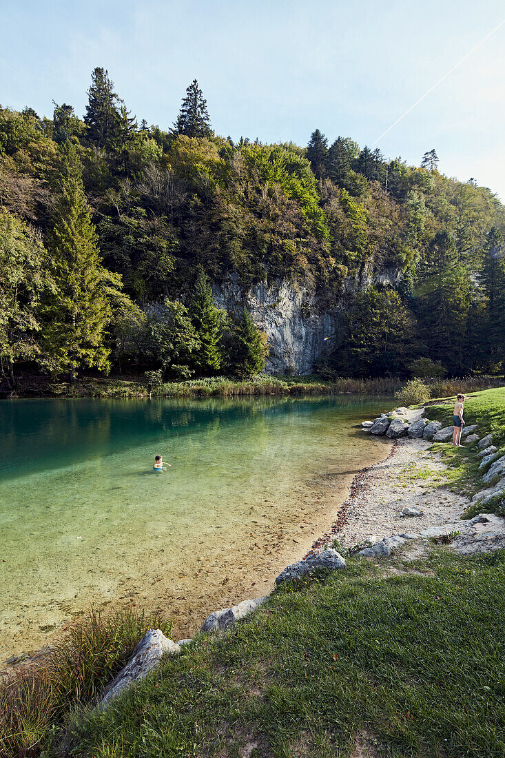 Person im Lamar-See mit bewaldeter Felsenküste