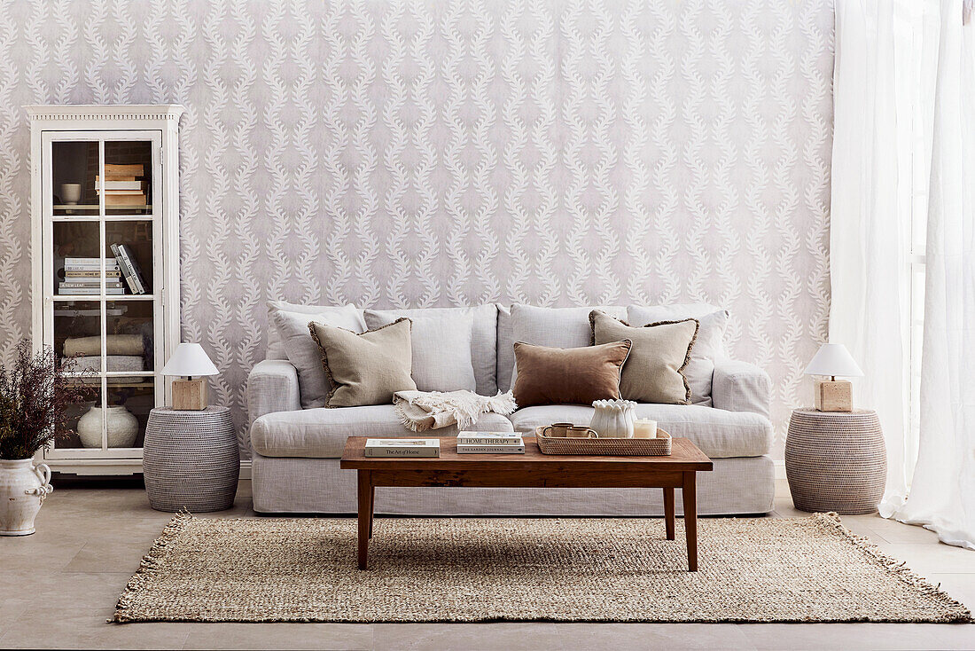 Living room with light grey sofa, wooden table and patterned wallpaper