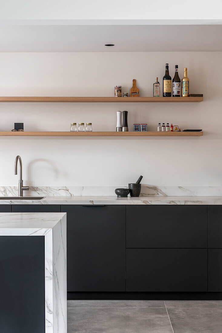 Modern kitchen with marble surfaces, black cabinets and open wooden shelves