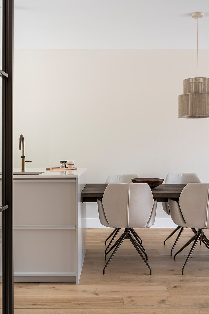 Modern, bright kitchen with customised table and beige upholstered chairs