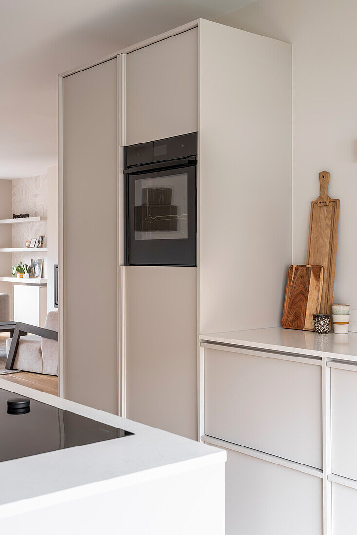 Modern, light-coloured fitted kitchen with integrated oven and cooking island