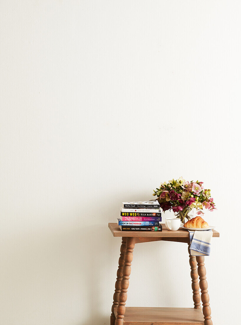 Wooden stool with bouquet of flowers, books and croissant