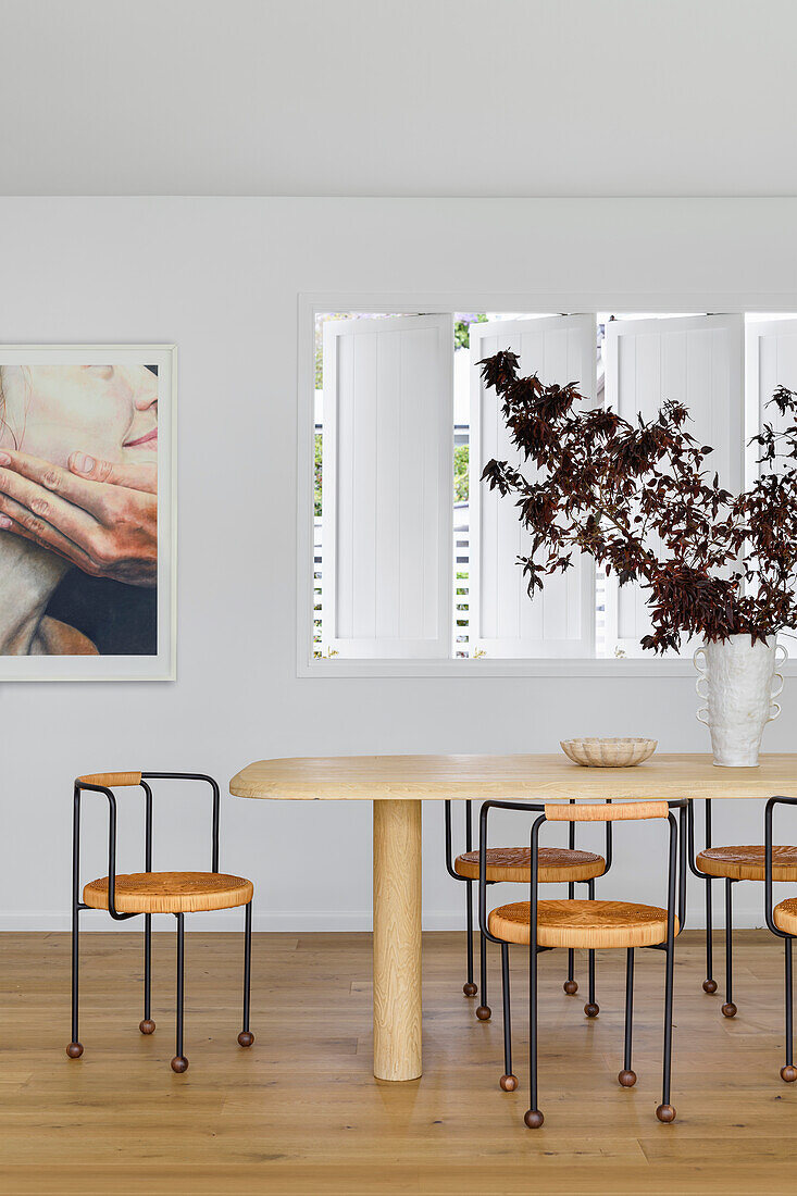 Modern dining area with wooden table and sculptural dried bouquet