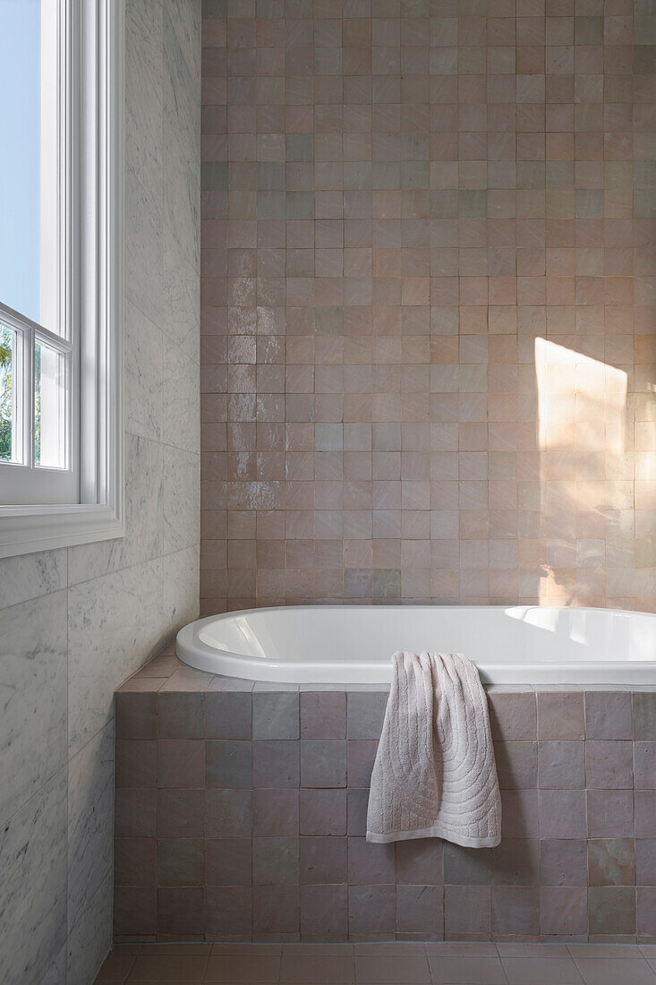 Bathroom with bathtub, beige-coloured tiles and window