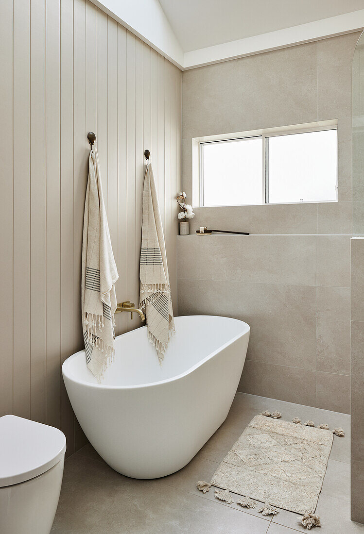 Freestanding bathtub and beige-coloured wood panelling in the modern bathroom