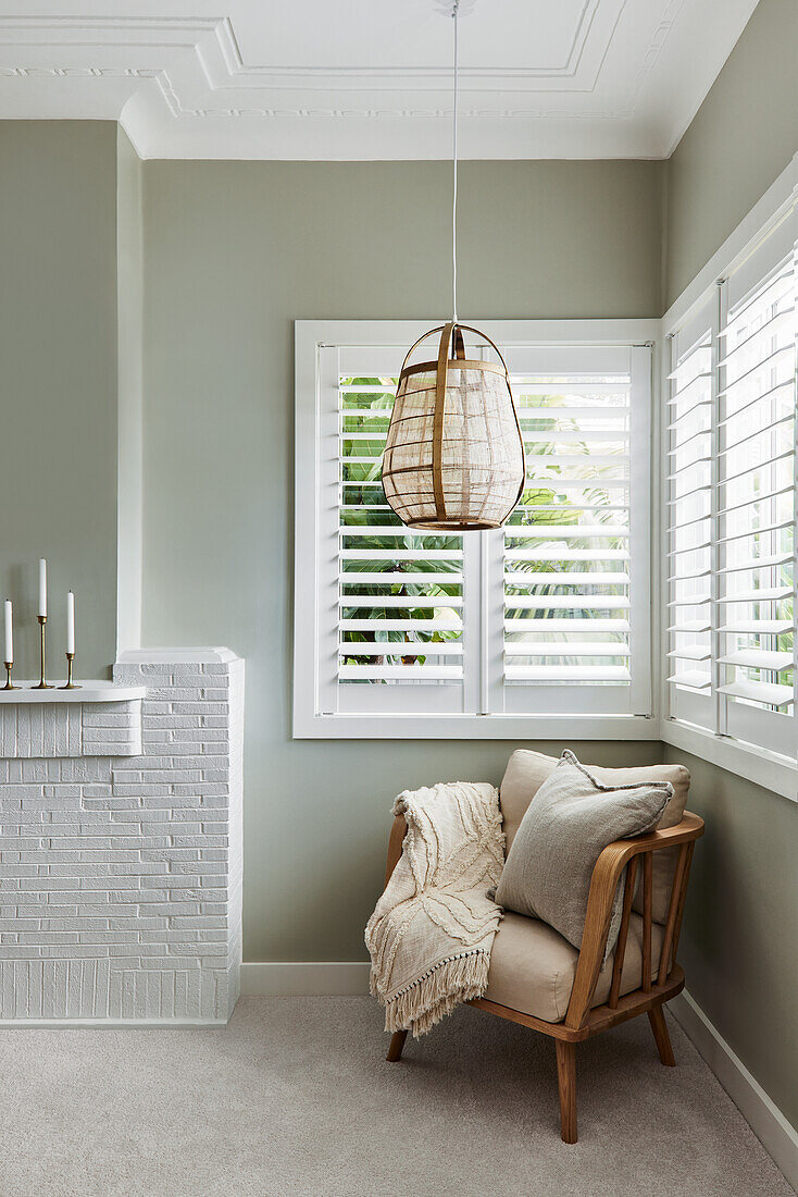 Cosy corner with armchair, blanket and cushions, green-painted wall