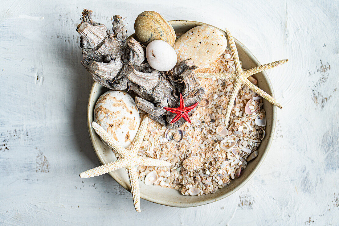 Bowl with sand, starfish and shells as a maritime decorative element