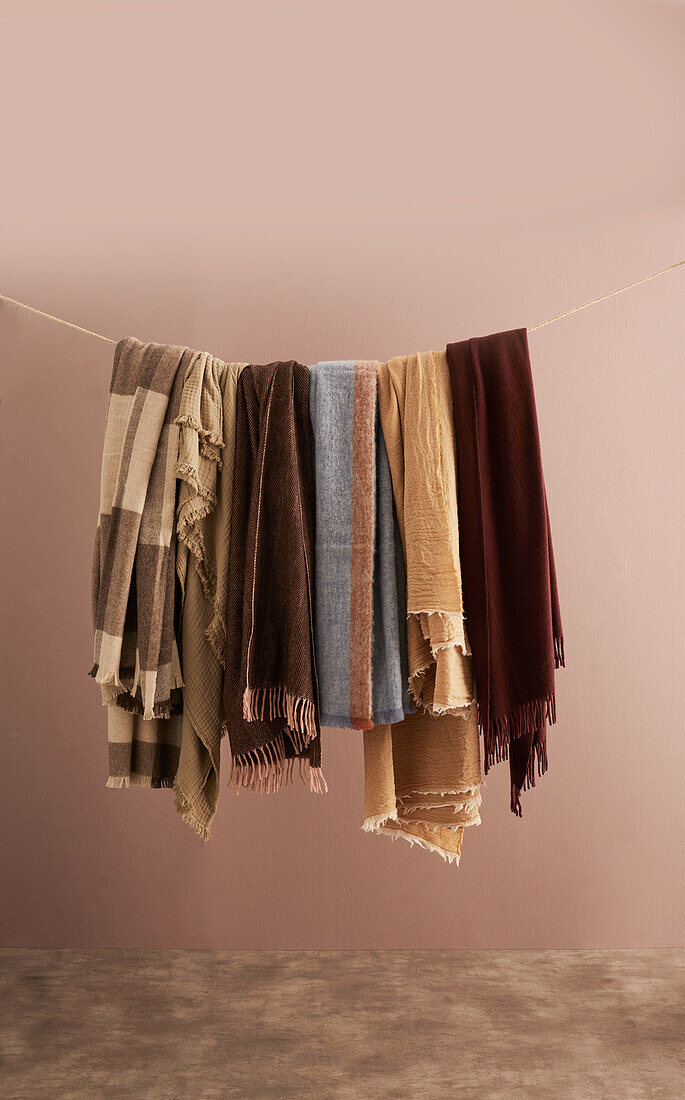 Various blankets in earth tones hanging on linen