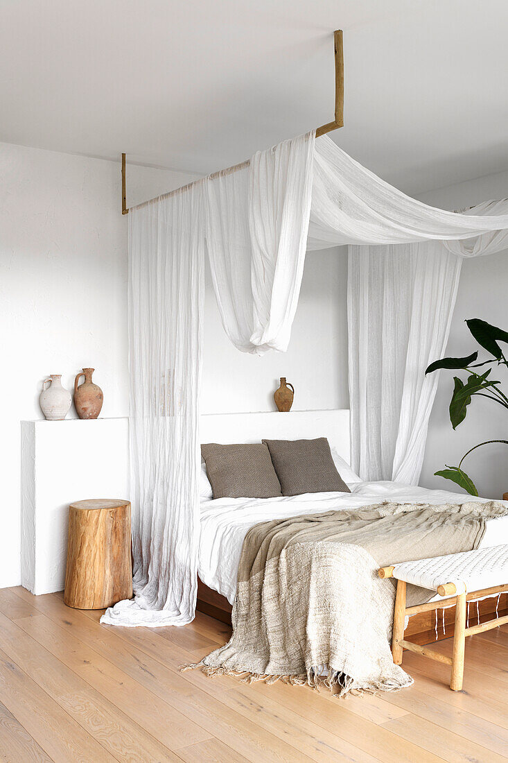 Bedroom with canopy of white fabric panels and wooden details