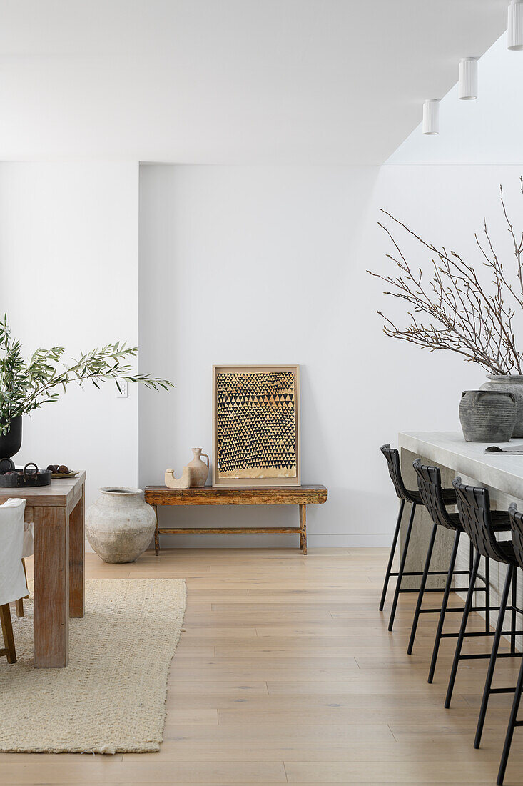 Open-plan living room with wooden table, bar stools and natural decorations