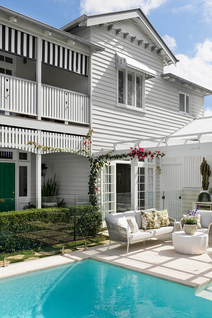 House with white wood panelling and modern outdoor area with pool